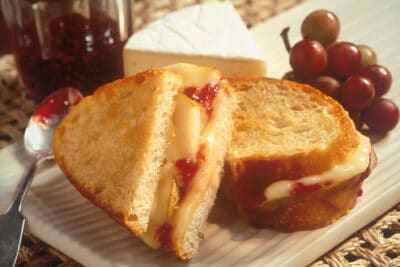 A dessert-style panini with grape jam and camembert cheese cut in two.