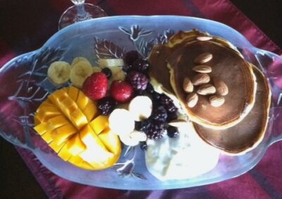 A charcuterie board made of fruit, cottage cheese pancakes, and more.