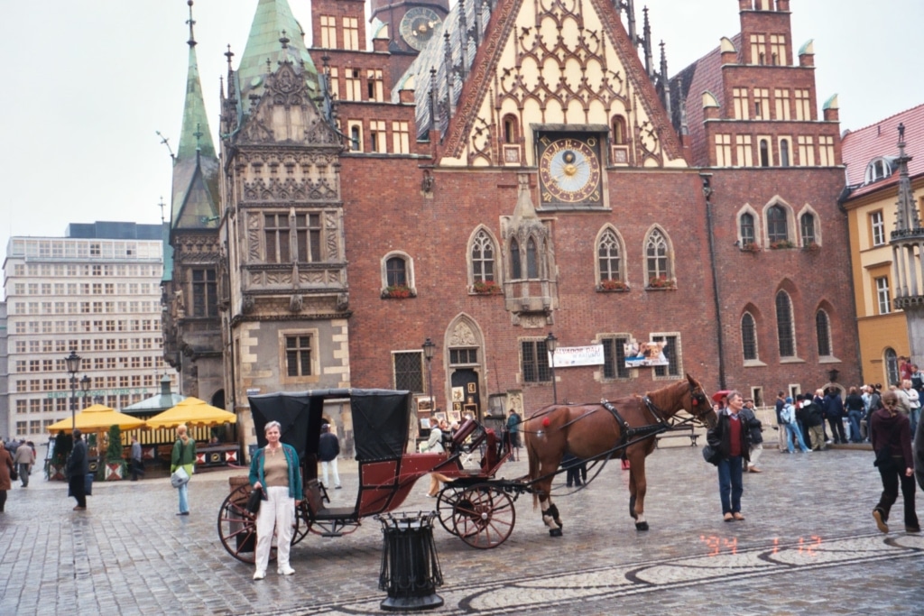 The outside of an older-style building, with a horse-drawn carriage in front of it.