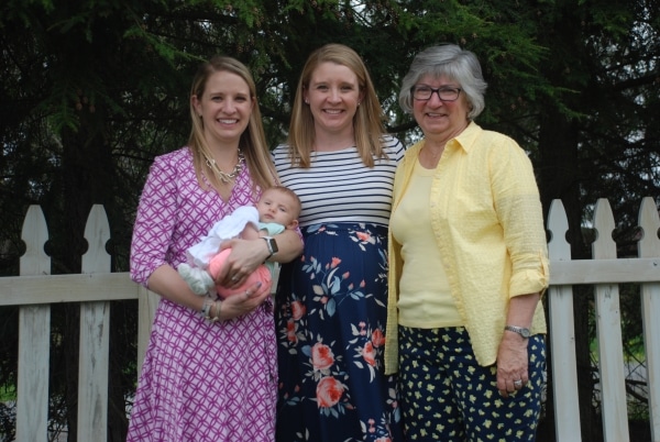 Three women smile with a newborn baby