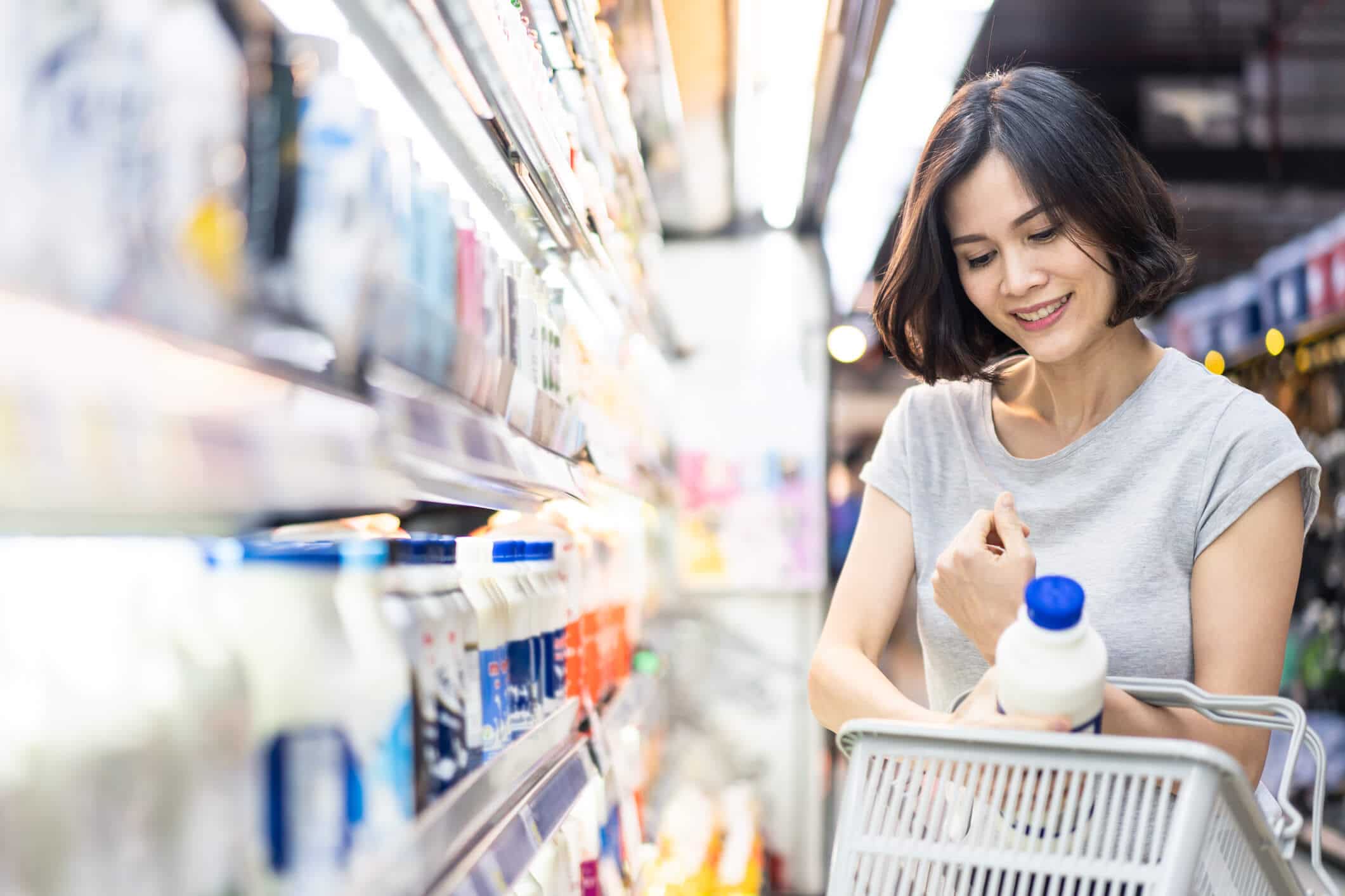 Woman placing a carton of milk in a shopping basket