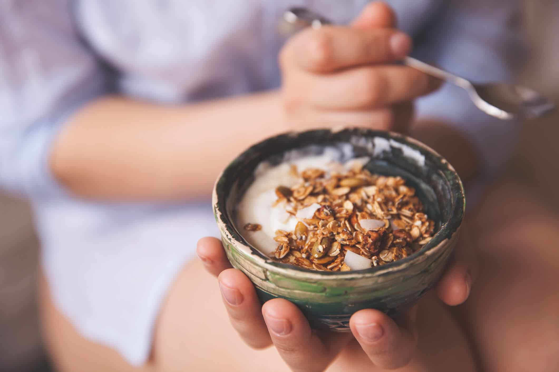 Person holding a bowl of yogurt with nuts