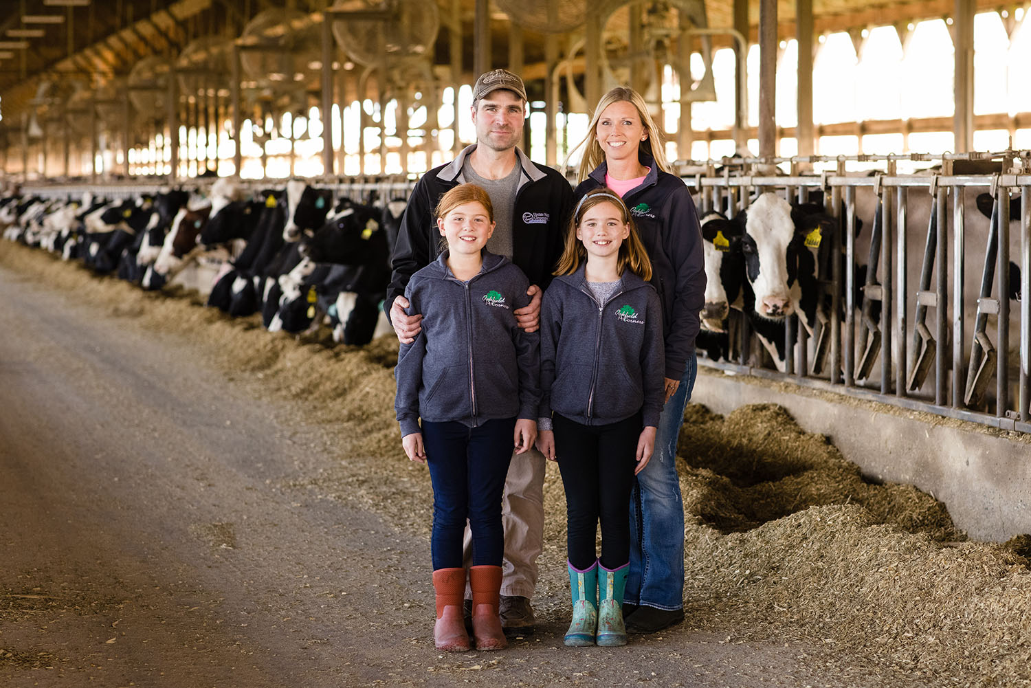 Family posing in front of a line of cows
