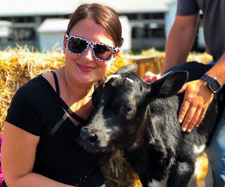 Woman smiling next to a calf
