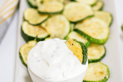 A serving of zucchini parmesan crisps served with a dipping sauce.